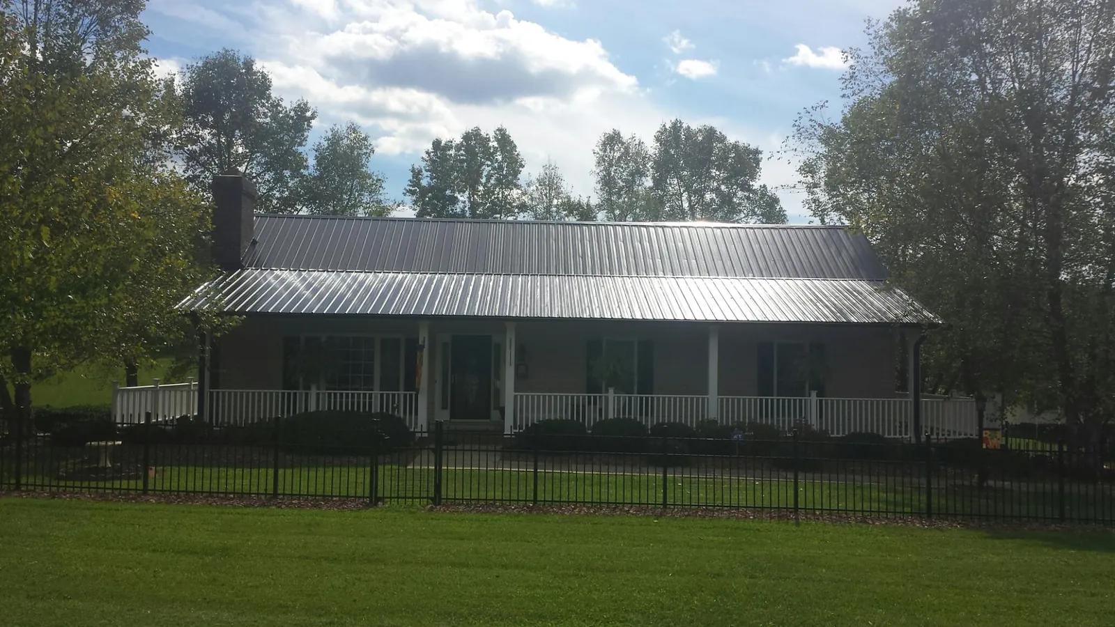 Gray metal roof on a brick ranch with a full width front porch — Gutter Guard Installation work by our crew in Painter